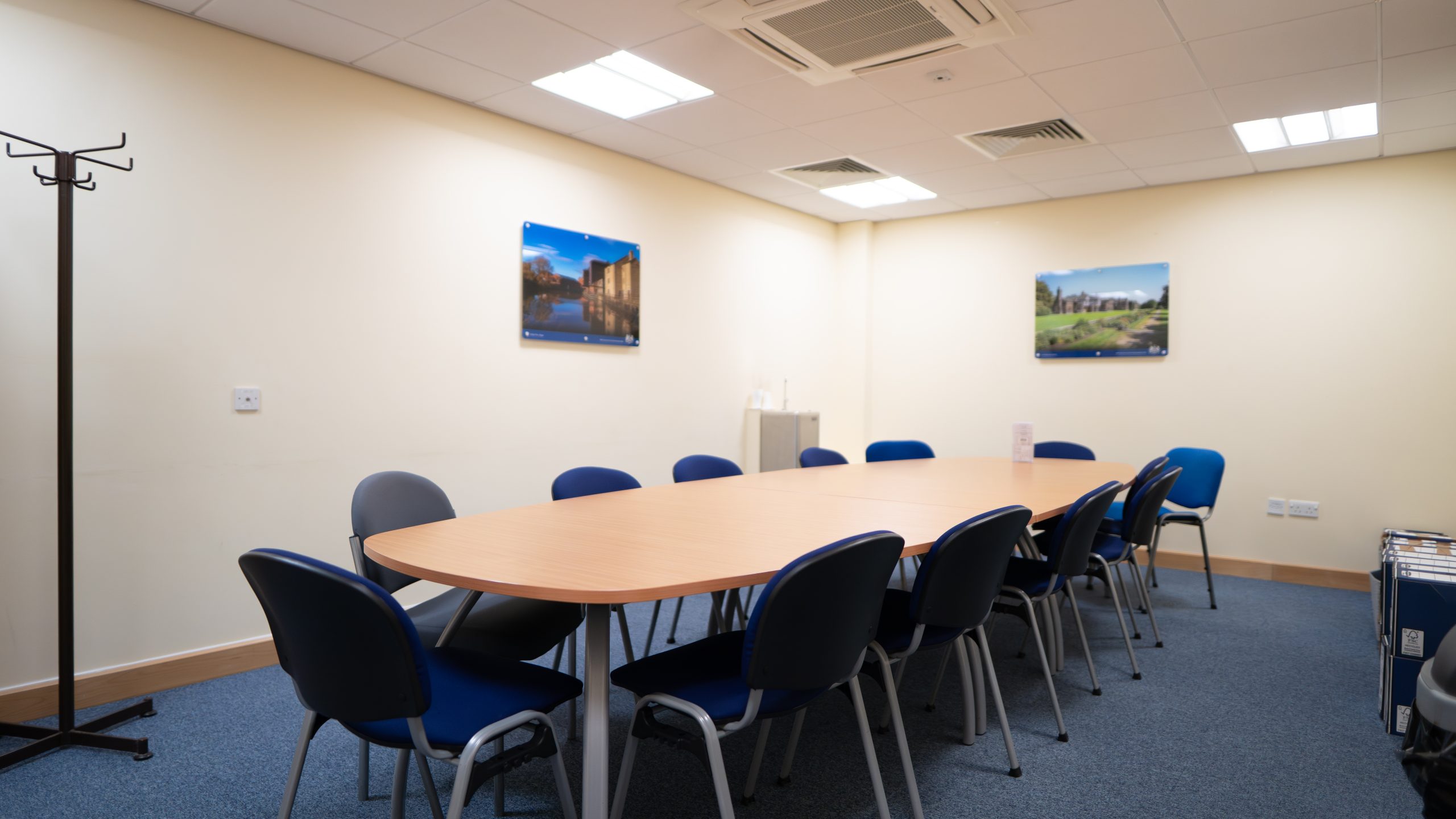 Meeting room with plain walls, a long boardroom table in the centre.